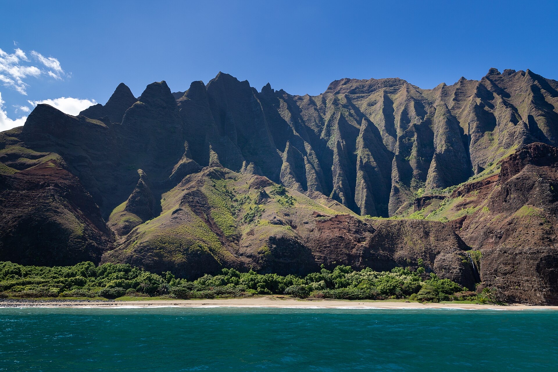 The fluted green cliffs of the Na Pali Coast above a beach and turquoise water